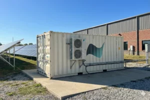 Conteneur de stockage d’énergie par batteries installé à côté de panneaux solaires photovoltaïques sur un site industriel