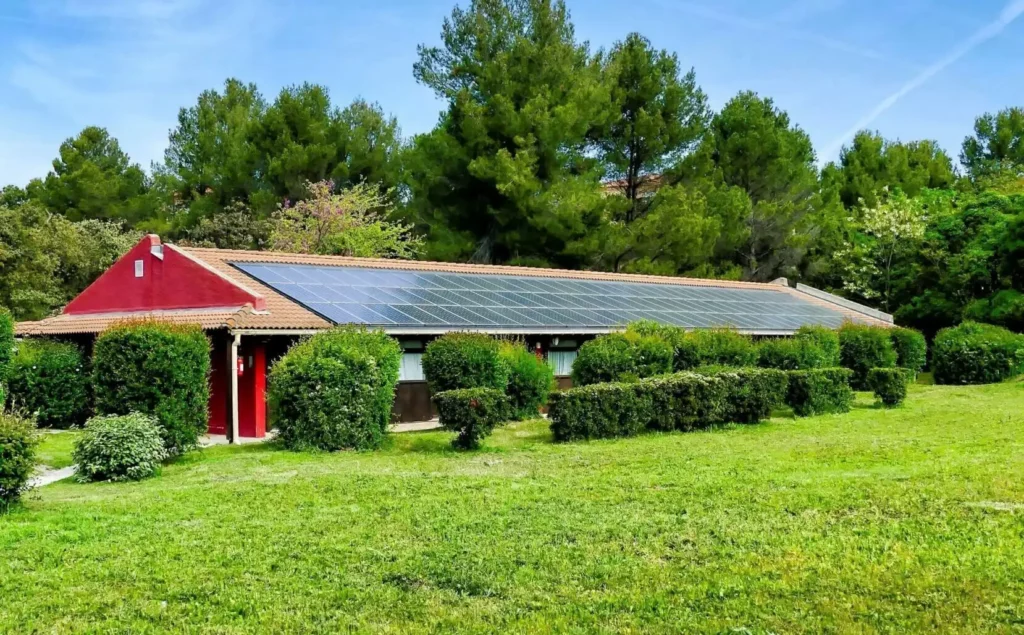 Bâtiment de collectivité avec toiture photovoltaïque produisant de l’énergie solaire renouvelable dans un environnement arboré